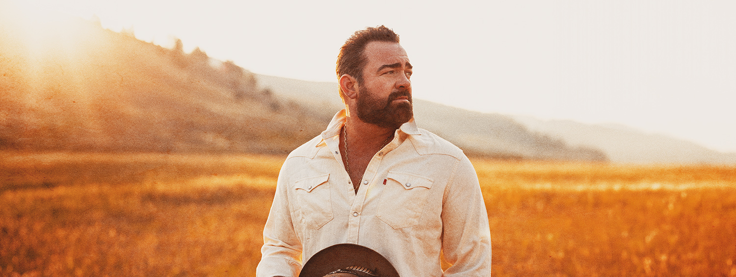 Lee Brice posing amongst a field gazing left